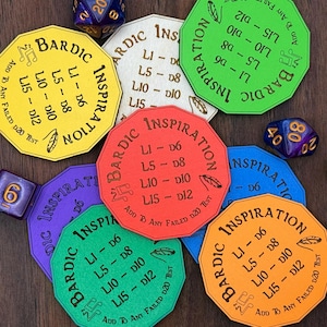 Puede incluir: Una colección de fichas de juego octogonales de colores con las palabras "Bardic Inspiration" y valores de tirada de dados impresos. Las fichas son de varios colores, incluyendo amarillo, rojo, verde, azul y naranja. También se ven dados.
