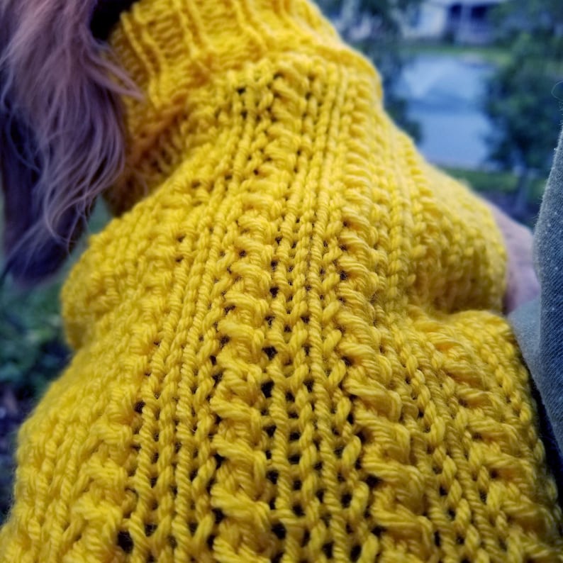 May include: A yellow knitted sweater for a small dog. The sweater has a cable knit pattern.