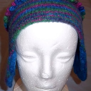 May include: A blue, green, and purple crocheted hat with a white styrofoam head form. The hat has a wide brim and a decorative band of colorful yarn.