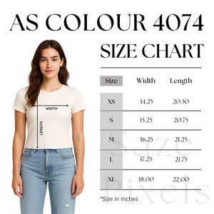 May include: A woman wearing a cream-colored t-shirt and blue jeans. The image includes a size chart with measurements in inches for XS to XL sizes. The text "AS COLOUR 4074 SIZE CHART" is at the top.