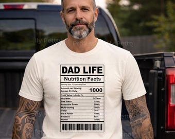 Könnte beinhalten: Cremefarbenes T-Shirt mit dem Text "DAD LIFE Nutrition Facts" in Schwarz. Die Grafik listet humorvolle "Nährstoffe" wie Papa-Witze, Schutzmacht und Humor auf. Das T-Shirt wird von einer Person getragen.