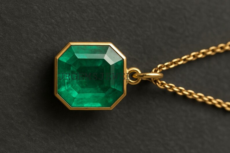 May include: A gold necklace featuring a large, emerald-cut green gemstone pendant. The pendant is set in a gold bezel and hangs from a delicate gold chain. The gemstone has a faceted surface, reflecting light. The necklace is displayed against a dark background.