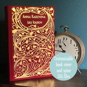 Op de afbeelding: Een rood boek getiteld "Anna Karenina" van Leo Tolstoj met een gouden bloemenontwerp. Een zilveren zakhorloge staat naast het boek. De afbeelding bevat ook de tekst "Customizable book cover and spine SVG files."