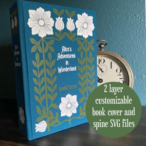 Może przedstawiać: Turkusowa okładka książki "Alicja w Krainie Czarów" Lewisa Carrolla, z białymi kwiatowymi i zielonymi wzorami liści. Tytuł książki jest wyśrodkowany, z nazwiskiem autora poniżej. Zielone koło mówi "2 layer customizable book cover and spine SVG files."