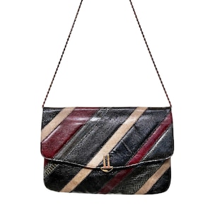 May include: A rectangular shoulder bag featuring a textured, snakeskin-patterned surface with diagonal stripes in black, burgundy, and beige. The bag includes a thin, dark brown braided chain strap and a gold-toned metal clasp on the front flap.