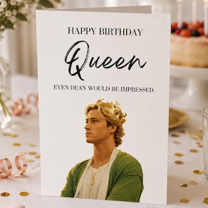 Può includere: Un biglietto d'auguri di compleanno rettangolare bianco con il testo HAPPY BIRTHDAY Queen EVEN DEAN WOULD BE IMPRESSED. Sotto il testo c'è un'immagine fotografica di una persona con capelli biondi che indossa una corona d'oro e una maglia verde.