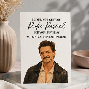 Könnte beinhalten: Eine weiße, rechteckige Geburtstagskarte mit einem Porträt von Pedro Pascal, der eine schwarze Lederjacke über einem hellen Hemd trägt. Der Text lautet: I COULDN'T GET YOU Pedro Pascal FOR YOUR BIRTHDAY SO I GOT YOU THIS CARD INSTEAD.