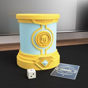 May include: A cylindrical game piece holder in yellow and light blue, with a diamond-shaped accent and a circular emblem. A white die and a card with the text "LEAGUE OF LEGENDS" are next to the holder.