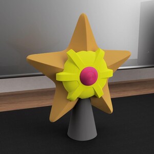 May include: A 3D-rendered star-shaped object with a yellow star, a yellow and pink circular design, and a gray conical base. The object is likely a decorative item or a stylized representation of a star.