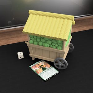Op de afbeelding: Een miniatuur houten kar met een geel rieten dak, gevuld met groene bollen. Een dobbelsteen en een ruilkaart liggen naast de kar. De kaart toont een persoon in groene kleding.