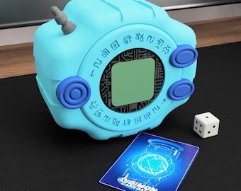 May include: A light blue Digivice toy with a small screen, three blue buttons, and a gray antenna. A Digimon card and a white die with black dots are next to the toy. The card has the text "DIGIMON CARD GAME".