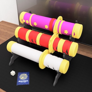 May include: Three decorative toy swords with yellow, red, pink, and white accents. The swords are displayed on black stands. A die and a card with the text "ONE PIECE CARD GAME" are in the foreground.
