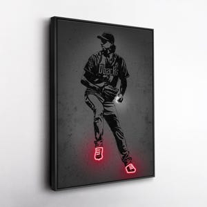 May include: A framed black and white print of a baseball player in action. The player is wearing a baseball uniform with the word "Dbacks" on the front. The player's shoes and the ground beneath them are highlighted with a red neon glow.