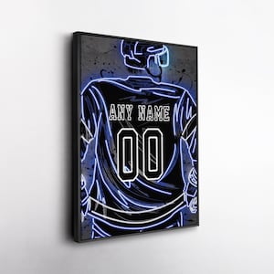 May include: Framed artwork featuring a hockey player's jersey with the text "ANY NAME" above the number "00". The design uses a neon blue outline on a black background, creating a striking visual effect. The artwork is encased in a black frame.
