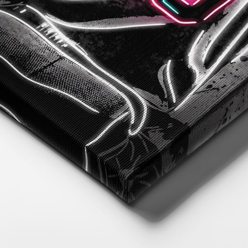 Op de afbeelding: Zwart-wit canvas print met een neonroze en turquoise hartontwerp. Het hart wordt vastgehouden door wit omrande handen. Het kunstwerk heeft een textuur, grunge-stijl achtergrond.