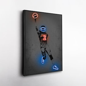 May include: A framed artwork featuring a football player in a dynamic pose, rendered in a neon-style design. The player is depicted in shades of gray, with neon blue and red accents highlighting the helmet, jersey number 2, and other details. The artwork is set against a textured gray background.