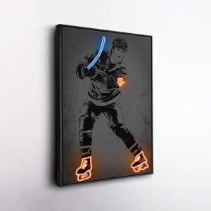 May include: Framed print of a hockey player in action, rendered in grayscale with neon blue and orange highlights. The hockey stick, jersey number, and skates are accentuated. The background is a textured grey. The artwork is framed in black.