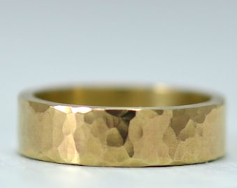 May include: A gold hammered band ring with a textured surface.