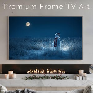 May include: A digital art print of a snowman in a snowy field under a full moon. The snowman wears a hat and scarf. The text "Premium Frame TV Art" is at the top. The image is displayed above a fireplace.