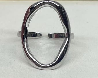May include: A silver-colored adjustable ring with an open oval design. The ring has a polished finish and a modern, minimalist aesthetic. The band is split at the back for adjustability.
