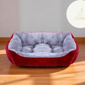 K&ouml;nnte beinhalten: Ein rechteckiges Haustierbett mit einem weichen, grauen Innenraum und einem tiefroten, cordartigen Au&szlig;enmaterial. Das Bett hat einen erh&ouml;hten Rand und ist auf Komfort ausgelegt. Das Bett steht auf einem Holzboden.
