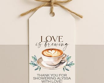 May include: A white gift tag with a brown twine bow. The tag features the text "Love is Brewing" above a coffee cup illustration with a heart-shaped design in the foam. The text "Thank you for showering Alyssa with love!" is below the coffee cup.
