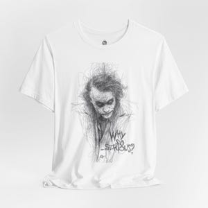 May include: White t-shirt featuring a black and white sketch of a character with messy hair and the text "Why so serious?" The graphic is a detailed line drawing. The shirt has short sleeves and a crew neck.