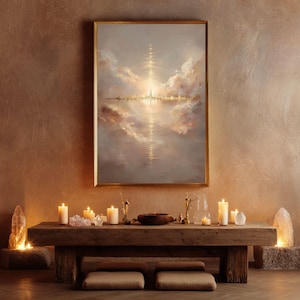 Puede incluir: Una pintura enmarcada con un borde dorado representa un paisaje celestial con un horizonte urbano reflejado en el agua. La pintura cuelga sobre una mesa de madera con velas, cristales y objetos decorativos. Dos cojines están debajo.