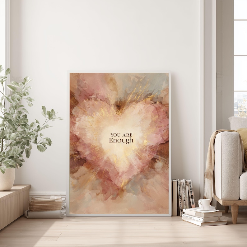 May include: Framed art print featuring a watercolor heart design in shades of pink, gold, and brown. The words "YOU ARE Enough" are centered within the heart. The artwork is displayed in a bright, airy room.