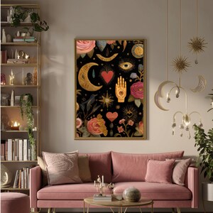 Peut inclure: Une impression d'art encadr&eacute;e avec un fond noir orn&eacute; d'&eacute;l&eacute;ments c&eacute;lestes et floraux dor&eacute;s et rouges. Le motif comprend un croissant de lune, une main, des c&oelig;urs, des &eacute;toiles et des roses. L'&oelig;uvre est expos&eacute;e au-dessus d'un canap&eacute; en velours rose.