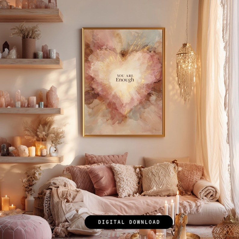 May include: A framed print with a heart-shaped design in shades of pink, gold, and beige, with the words "YOU ARE Enough" in the center. The artwork hangs above a sofa with pink and beige pillows. The room is decorated in a bohemian style.