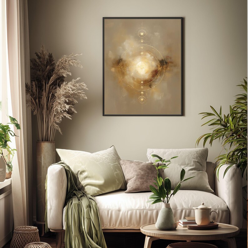 May include: A framed abstract art print with a gold and brown color palette hangs above a cream-colored sofa. The artwork features a circular design with radiating lines and a central bright light. The room is decorated with plants and neutral-toned furniture.