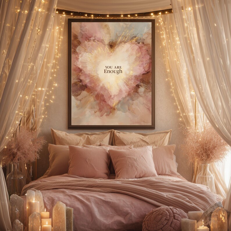 May include: A bedroom scene with a large framed artwork featuring a heart-shaped design in shades of pink, peach, and gold. The artwork has the text "YOU ARE Enough". The bed is covered in pink bedding with matching pillows. Fairy lights and candles add to the ambiance.