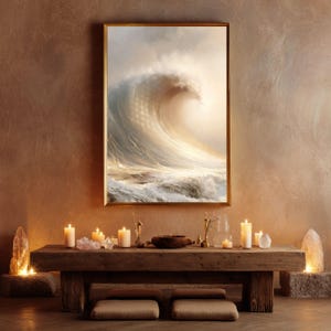Puede incluir: Una impresión de arte mural enmarcada que representa una gran ola oceánica rompiendo en tonos crema, beige y blanco. La obra se exhibe sobre una mesa de madera rústica larga con varias velas de pilar encendidas y piedras de cristal.