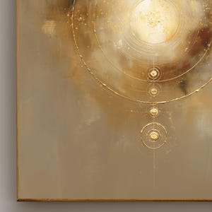 May include: Abstract art piece with a gold and neutral color palette. The artwork features concentric circles and a central bright spot, with gold accents and a textured appearance. The piece is framed.