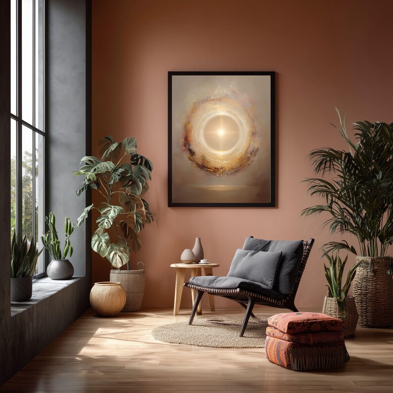 May include: A framed abstract art print with a bright, central light source surrounded by swirling colors of gold, brown, and cream. The artwork hangs on a terracotta-colored wall in a room with plants and a wicker chair.