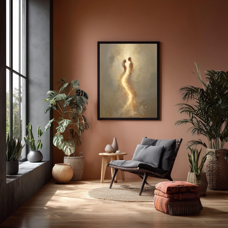 May include: A framed wall art print featuring an abstract, glowing silhouette of two figures facing each other, rendered in warm golden and beige tones. The artwork is displayed on a solid terracotta-colored wall above a wooden side table and chair.