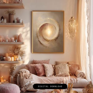 May include: A living room scene with a large framed abstract art piece in gold and neutral tones. The artwork features a spiral design with a bright center. The room includes a sofa with pink and cream pillows, candles, and decorative shelves with crystals.