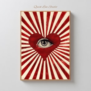 Op de afbeelding: Een ingelijste kunstdruk met een rood hart met een oog in het midden, tegen een achtergrond van rode en crèmekleurige stralen. Het kunstwerk is gesigneerd "Quick Line Studio". Het thema is surrealistisch en symbolisch.
