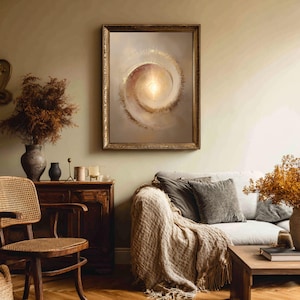 May include: A framed abstract art print featuring a spiral design with a bright center. The artwork has a gold frame and is displayed in a living room setting with a sofa, wooden furniture, and decorative items.