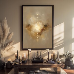 May include: A framed abstract art print with a celestial design in gold and beige tones. The artwork is displayed above a wooden table with candles, decorative objects, and a plant. The overall aesthetic is warm and inviting.