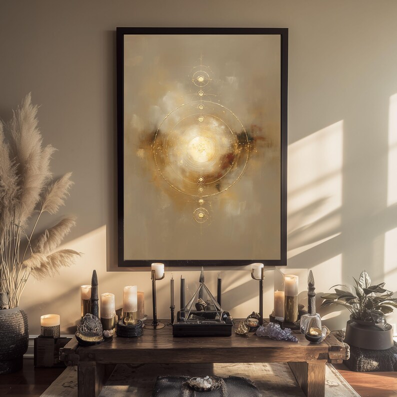 May include: A framed abstract art print with a celestial design in gold and beige tones. The artwork is displayed above a wooden table with candles, decorative objects, and a plant. The overall aesthetic is warm and inviting.