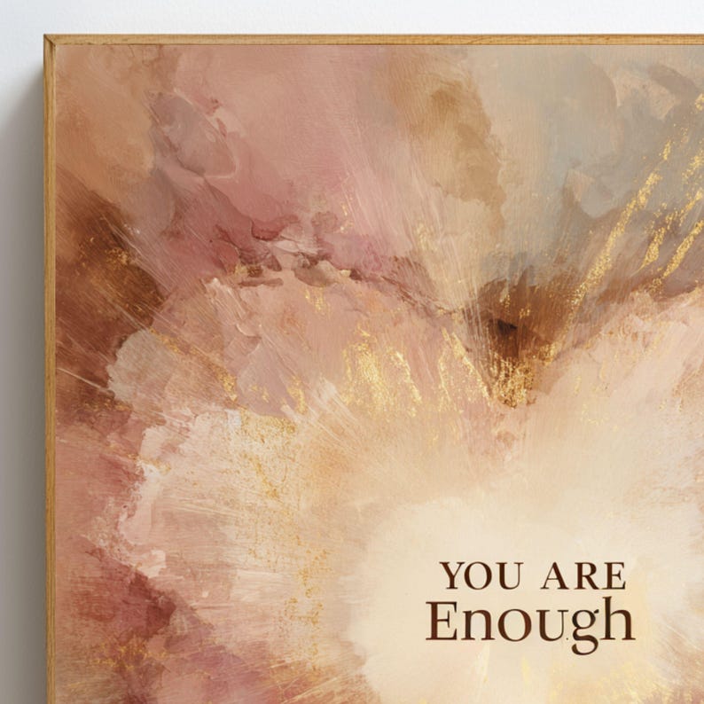 May include: Abstract art print in a wooden frame. The artwork features a blend of pink, peach, and gold tones, with the words "YOU ARE Enough" in a brown font. The painting has a textured, brushstroke effect.