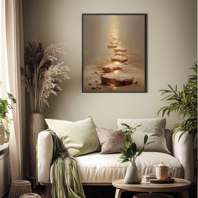 Op de afbeelding: Een ingelijste kunstdruk toont een pad van verlichte stapstenen die omhoog leiden. Het kunstwerk gebruikt warme, aardse tinten met een gouden licht. De print wordt weergegeven boven een cr&egrave;mekleurige bank met decoratieve kussens.
