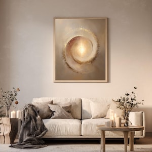 May include: A framed abstract art print featuring a spiral design in shades of beige, brown, and gold. The artwork hangs above a cream-colored sofa with throw pillows and a blanket. A wooden coffee table and side table with candles complete the living room setting.
