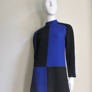 May include: A blue and black dress with a geometric pattern. The dress has a high neck and long sleeves.
