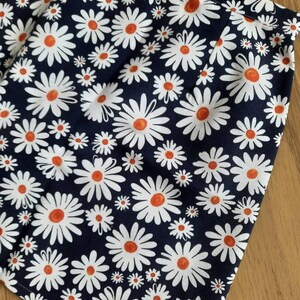May include: A navy blue skirt with a white daisy print. The daisies have orange centers.