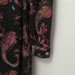 May include: A black long-sleeved dress with a pink and orange paisley pattern. The dress has a sparkly texture and a button on the cuff.