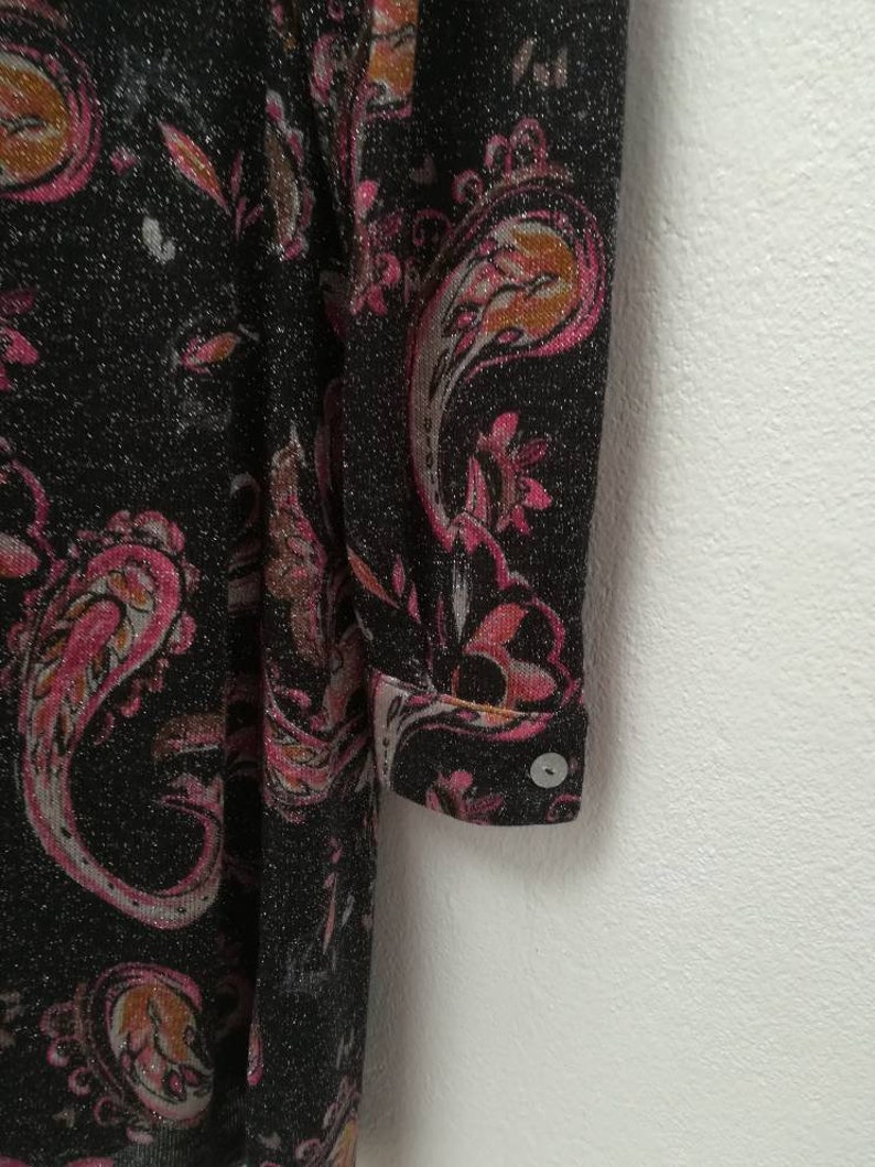 May include: A black long-sleeved dress with a pink and orange paisley pattern. The dress has a sparkly texture and a button on the cuff.