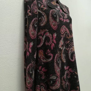 May include: A black long-sleeved dress with a paisley print in shades of pink, white, and brown. The dress has a collared neckline and a button closure.